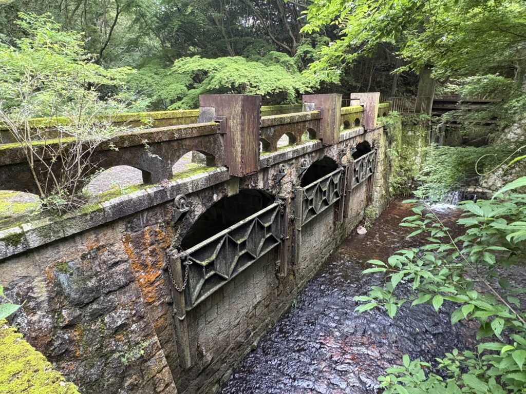 現在の烏原水源・締切堰堤の全景
キャプション：
烏原水源上流側に残る締切堰堤。鉄製扉が確認できるが、立ヶ畑堰堤本体の鉄扉とは別機構に見える。
