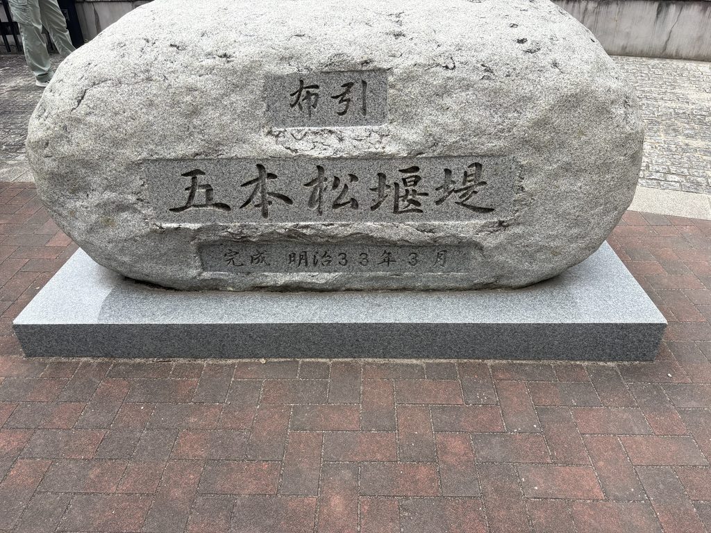 「布引五本松堰堤　完成明治三十三年三月」と刻まれた石。現在「布引ダム」と呼ばれる堰堤の歴史的名称が現地にも残る。2026年8月27日撮影。