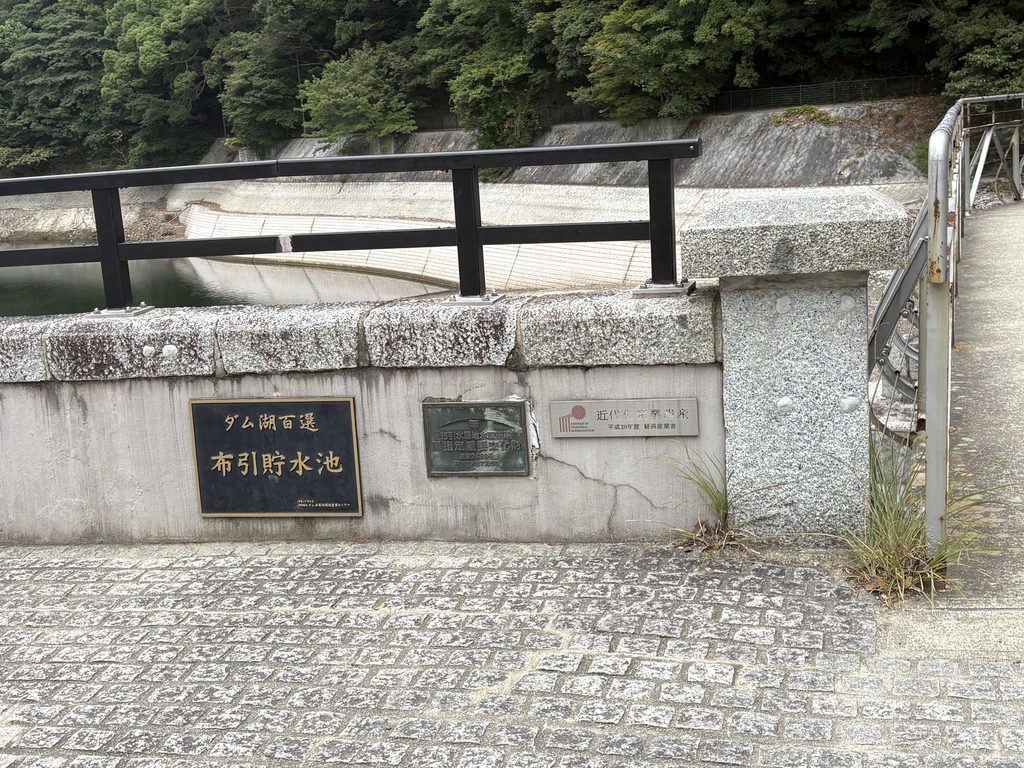 布引貯水池・五本松堰堤に掲げられた「ダム湖百選」「国指定重要文化財」「近代化産業遺産」のプレート。歴史的価値を評価されながら、現在も水道施設として使われている。2026年8月27日撮影。