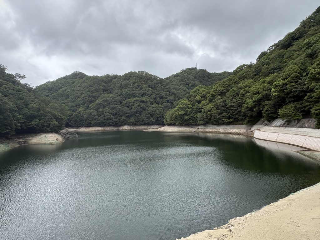 水位が下がった布引貯水池。池の周囲には普段は水面下にある土の部分が露出していた。2026年8月27日撮影。